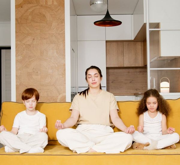 Child sitting calmly with eyes closed in a simple meditation pose.